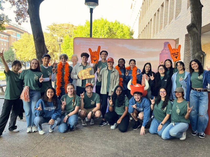 Student volunteers gather in front of a backdrop at the annual McKetta Tailgate.