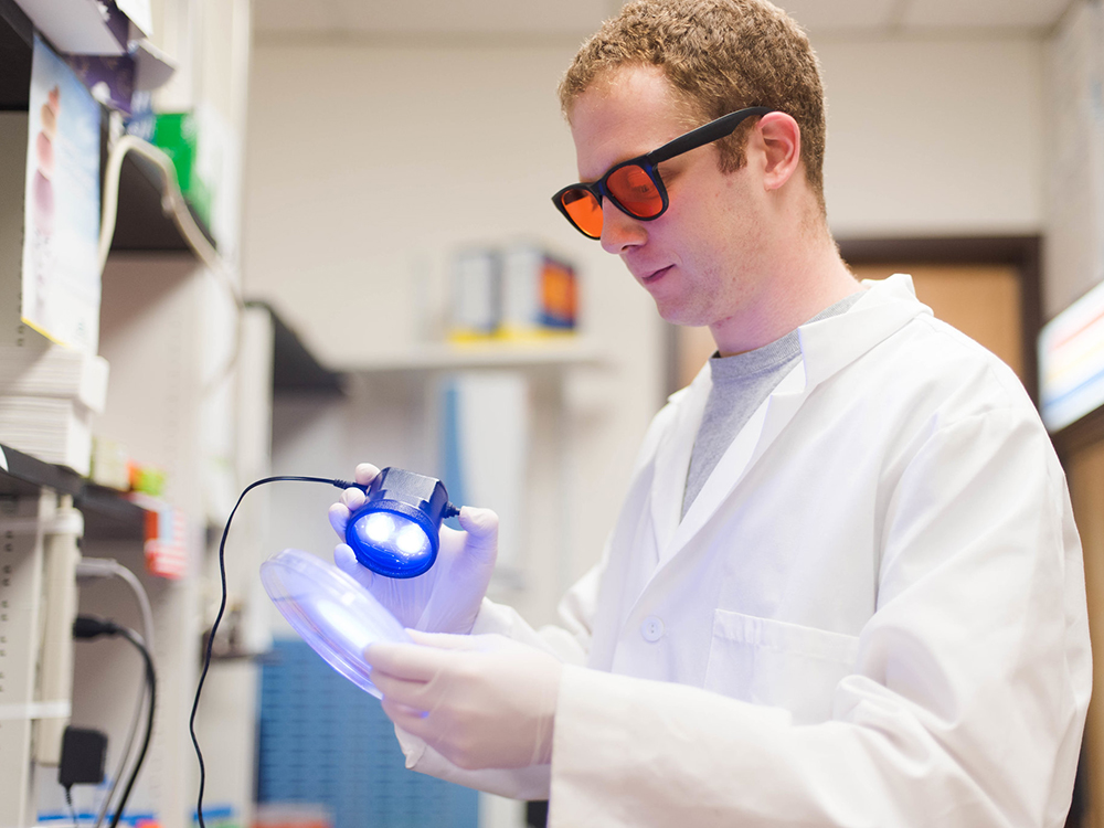 man in lab wearing orange glasses holding light
