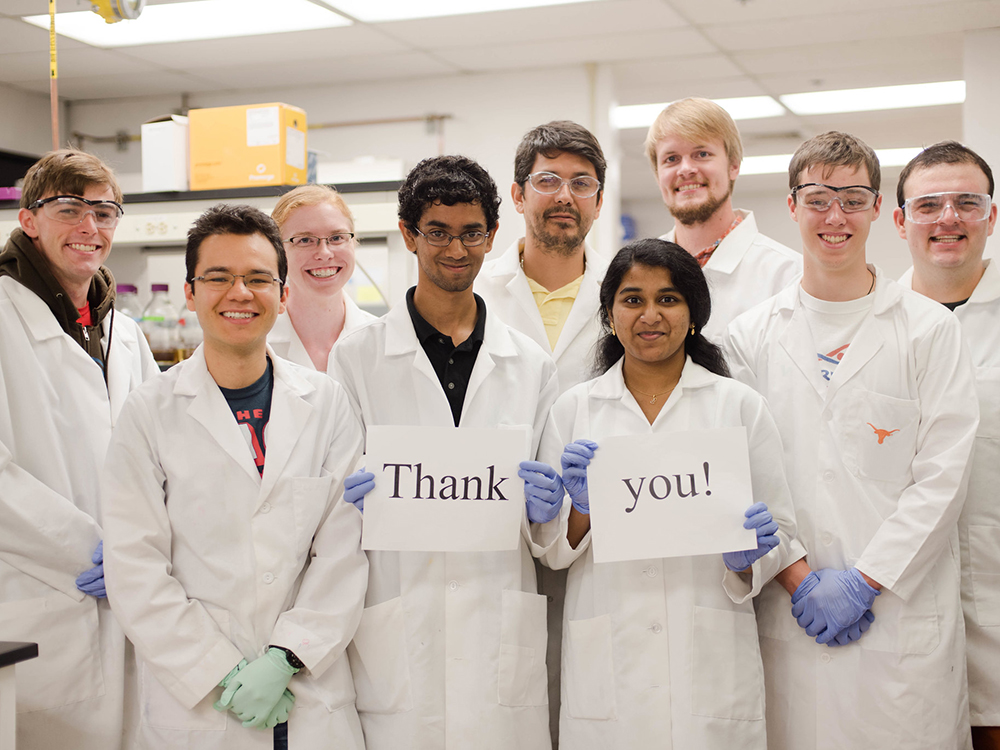 group of students in lab coats holding thank you sign