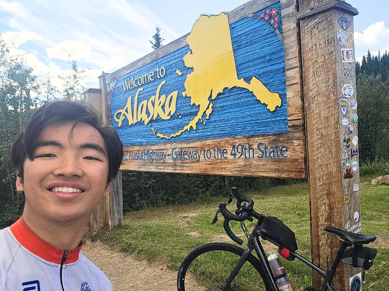 Jason Wang poses in front of the Welcome to Alaska sign. 