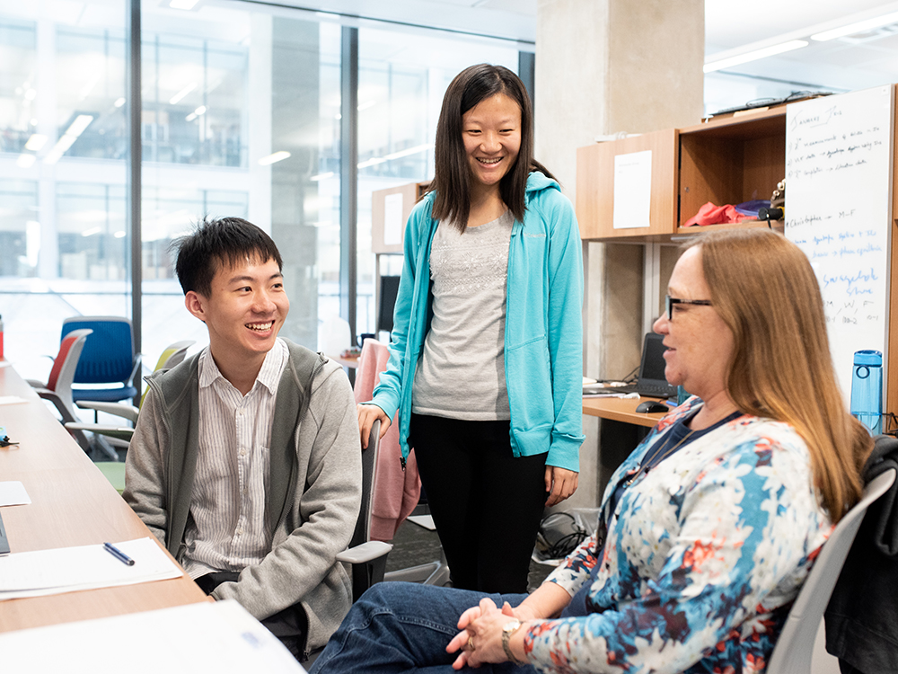 two students in office with professor