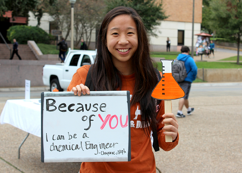 student holding sign saying "because of you I can be an engineer"