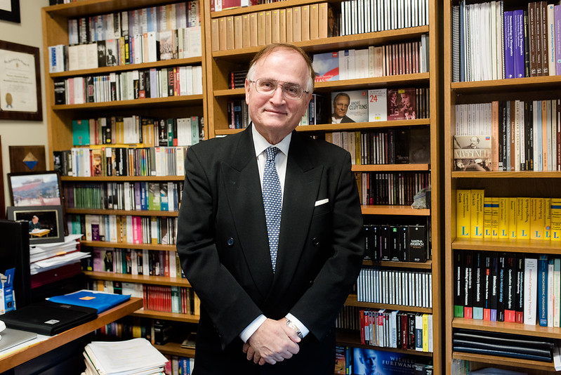 Texas Engineer Nicholas Peppas standing with hands clasped in front of bookshelves
