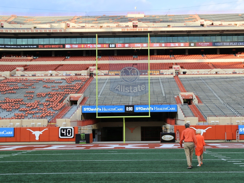 Dennis Griffith and Louise Richman walking on the field of UT Austin stadium