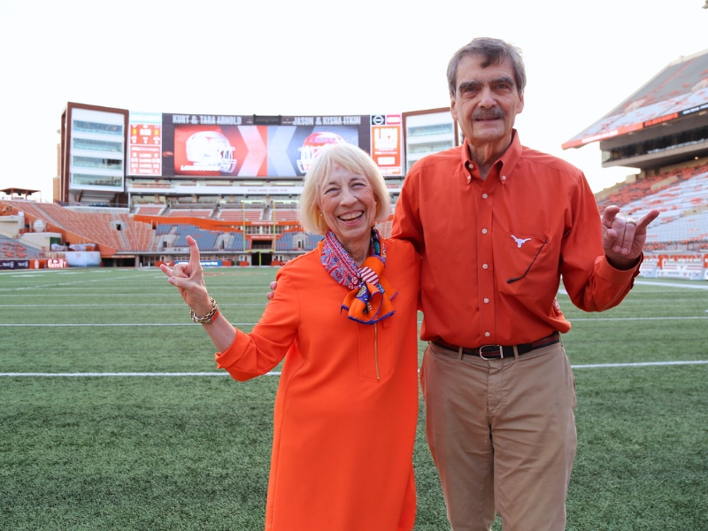 Dennis Griffith and Louise Richman smiling on field of UT Austin stadium