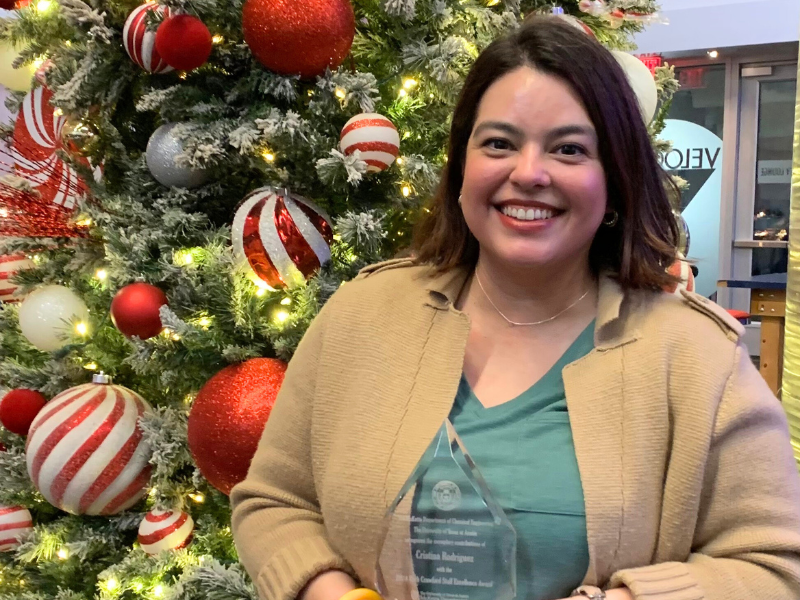 Cristina Rodriguez holding Crawford Staff Excellence Award in front of Christmas tree