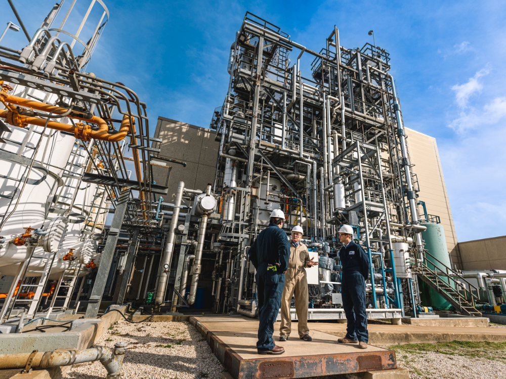 People talking outside research facility with many vertical pipes