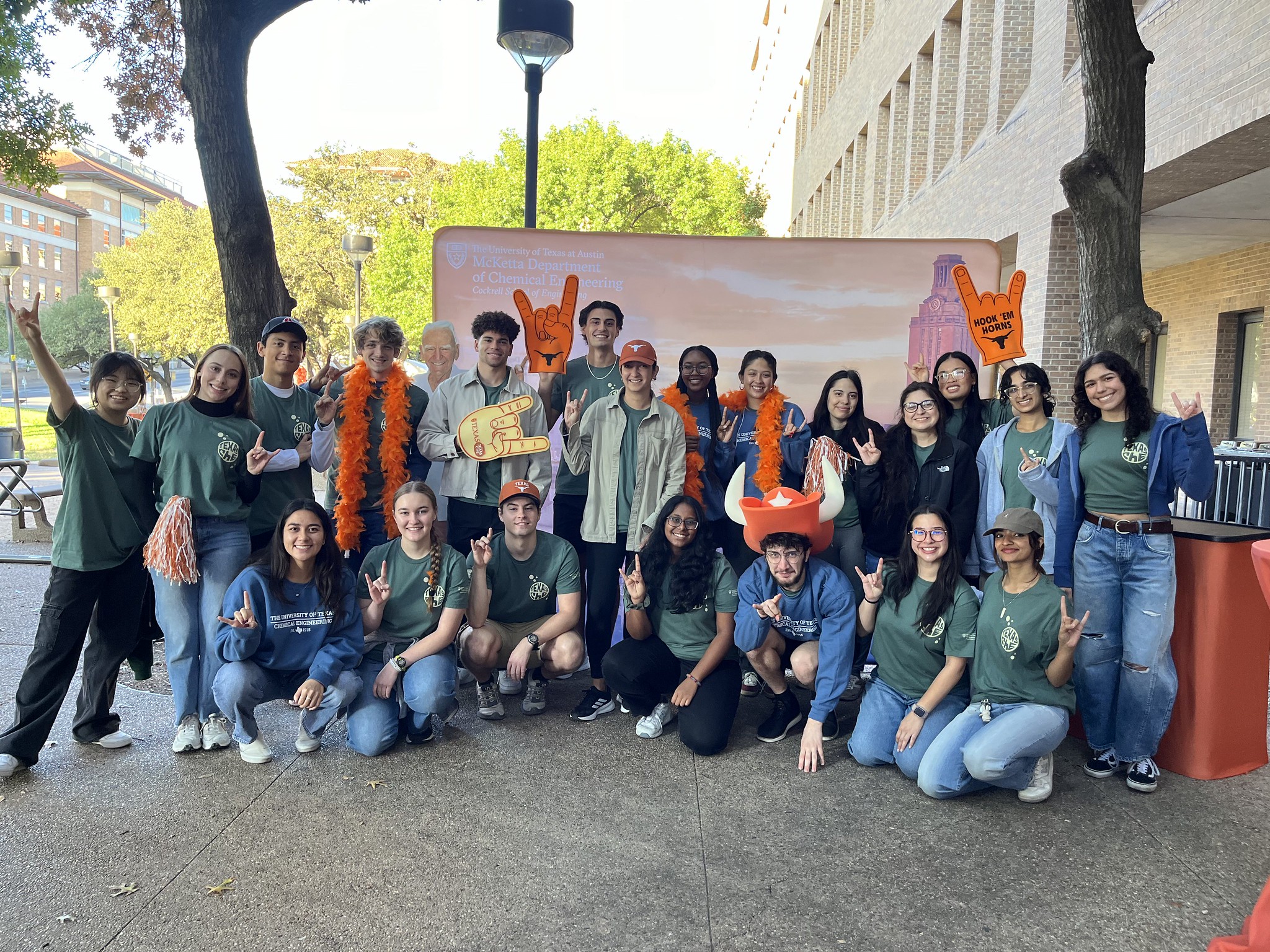 A large group of Texas ChE students smiling together in front of backdrop