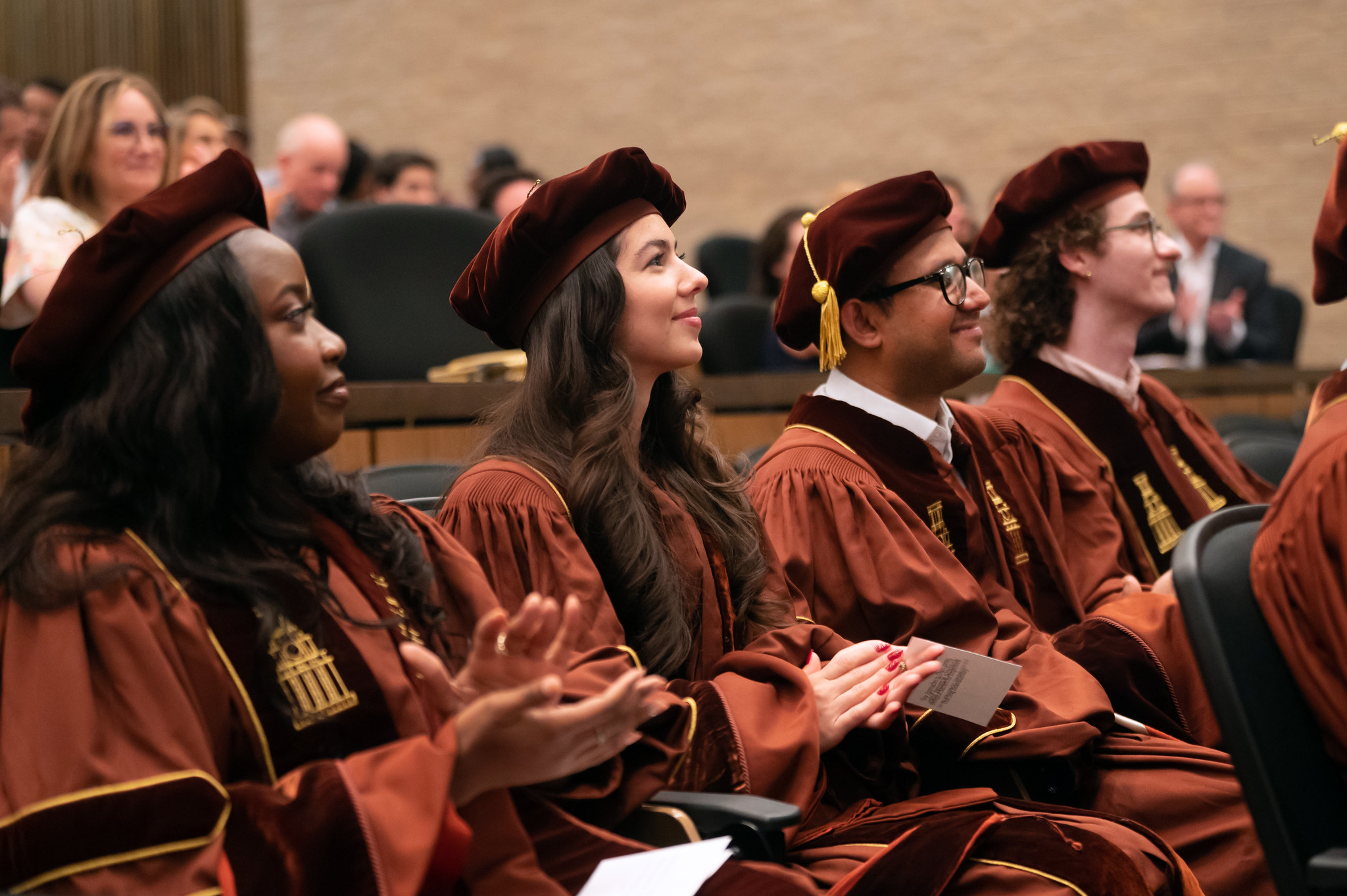 Texas ChE Ph.D. graduates sitting in audience while wearing caps and gowns